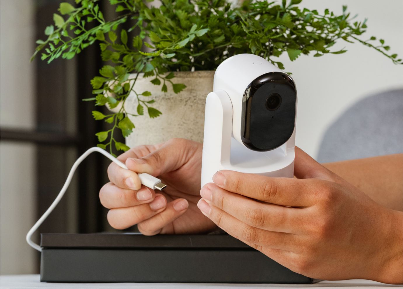 A person plugging in a cord in the Arlo Essential Pan Tilt Indoor camera
