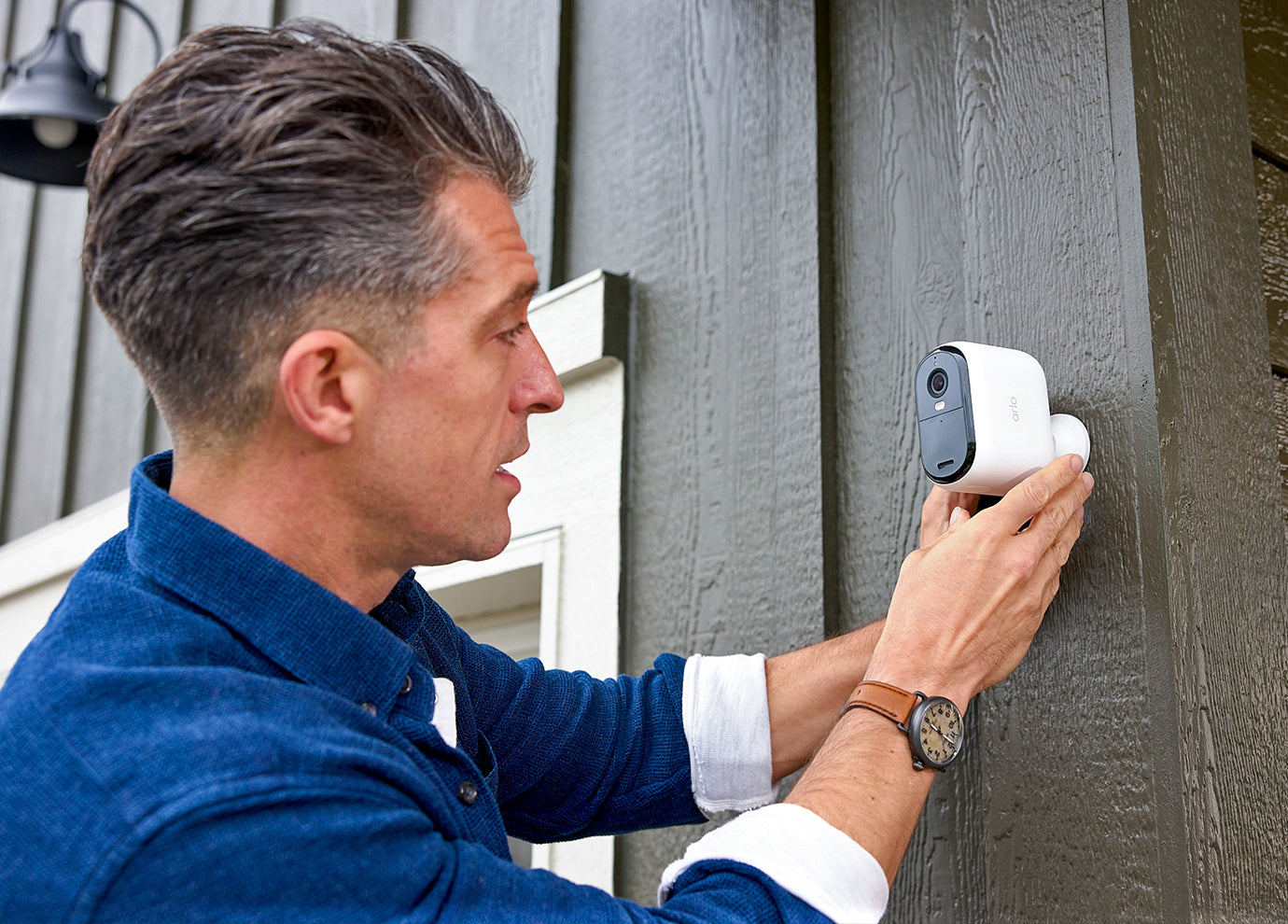 A man mounting the Arlo Essential 3rd Gen XL camera on a side of a house