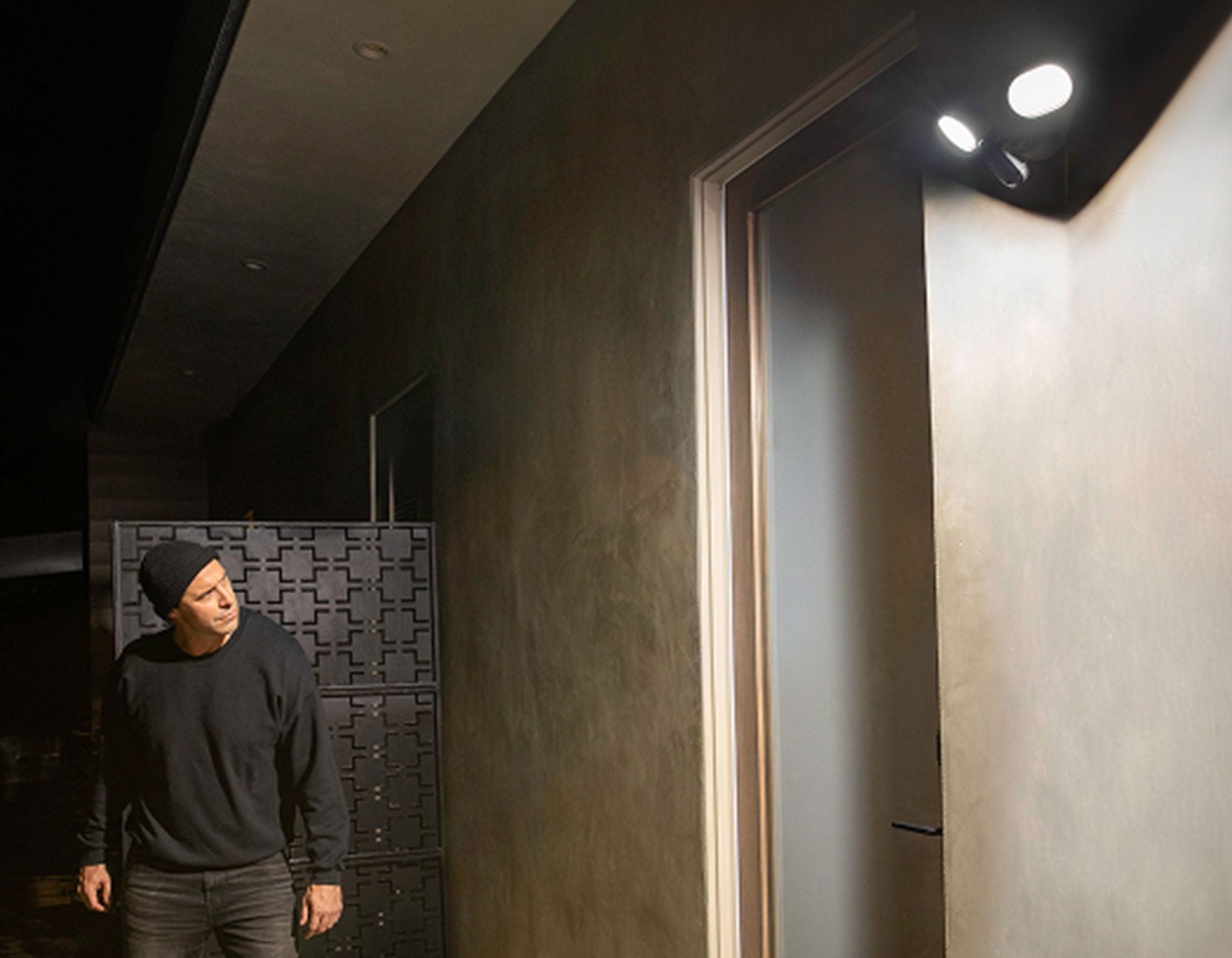 Burglar outside of a house with the Arlo Wired Floodlight shining a light