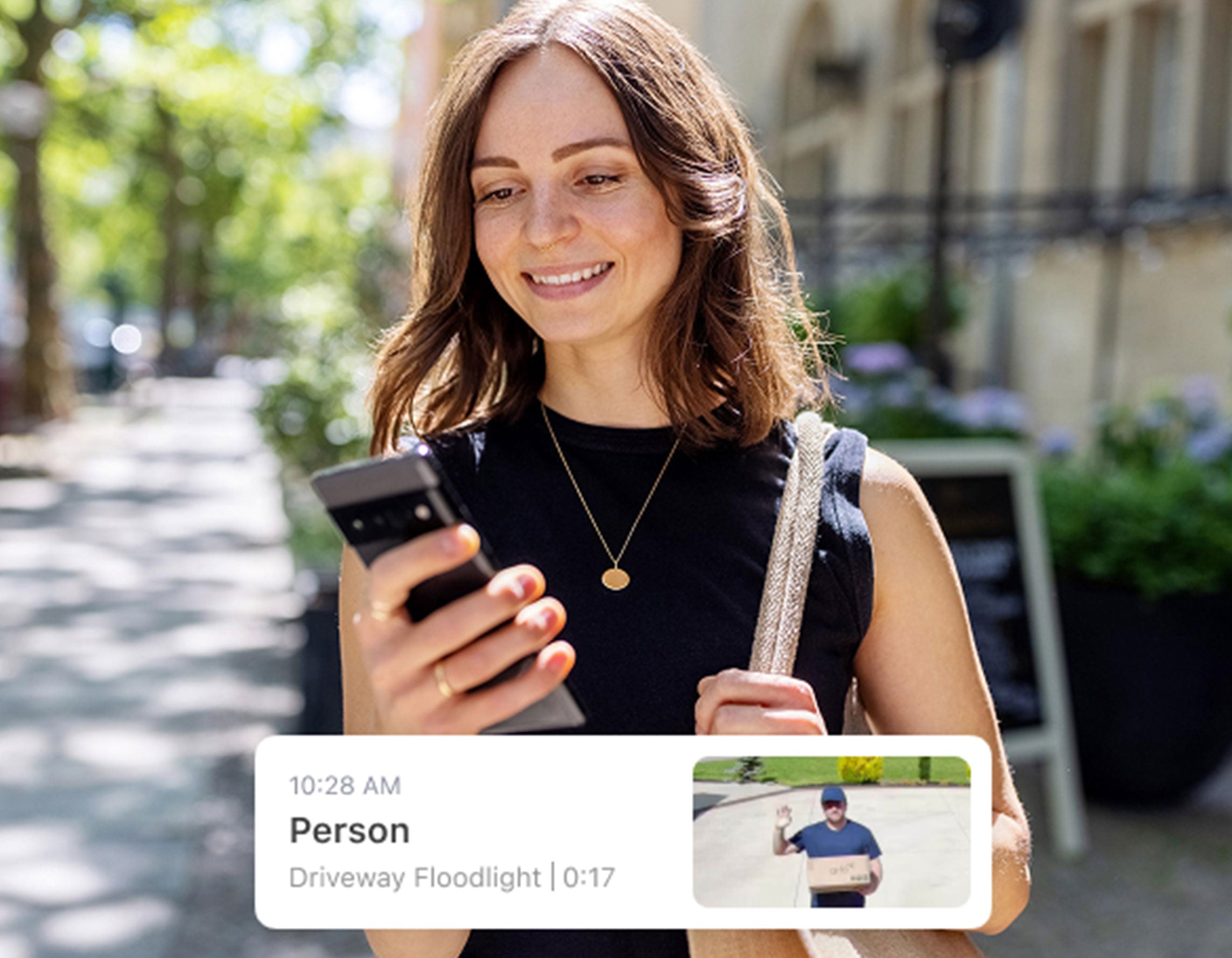 A woman looking at her phone with an Arlo Secure notification appearing