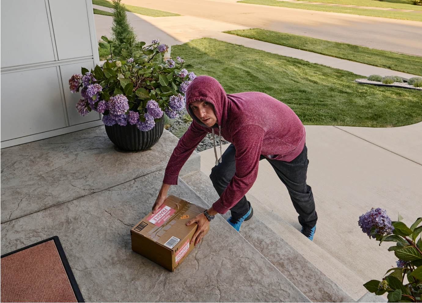 A burglar trying to steal a package off a front porch