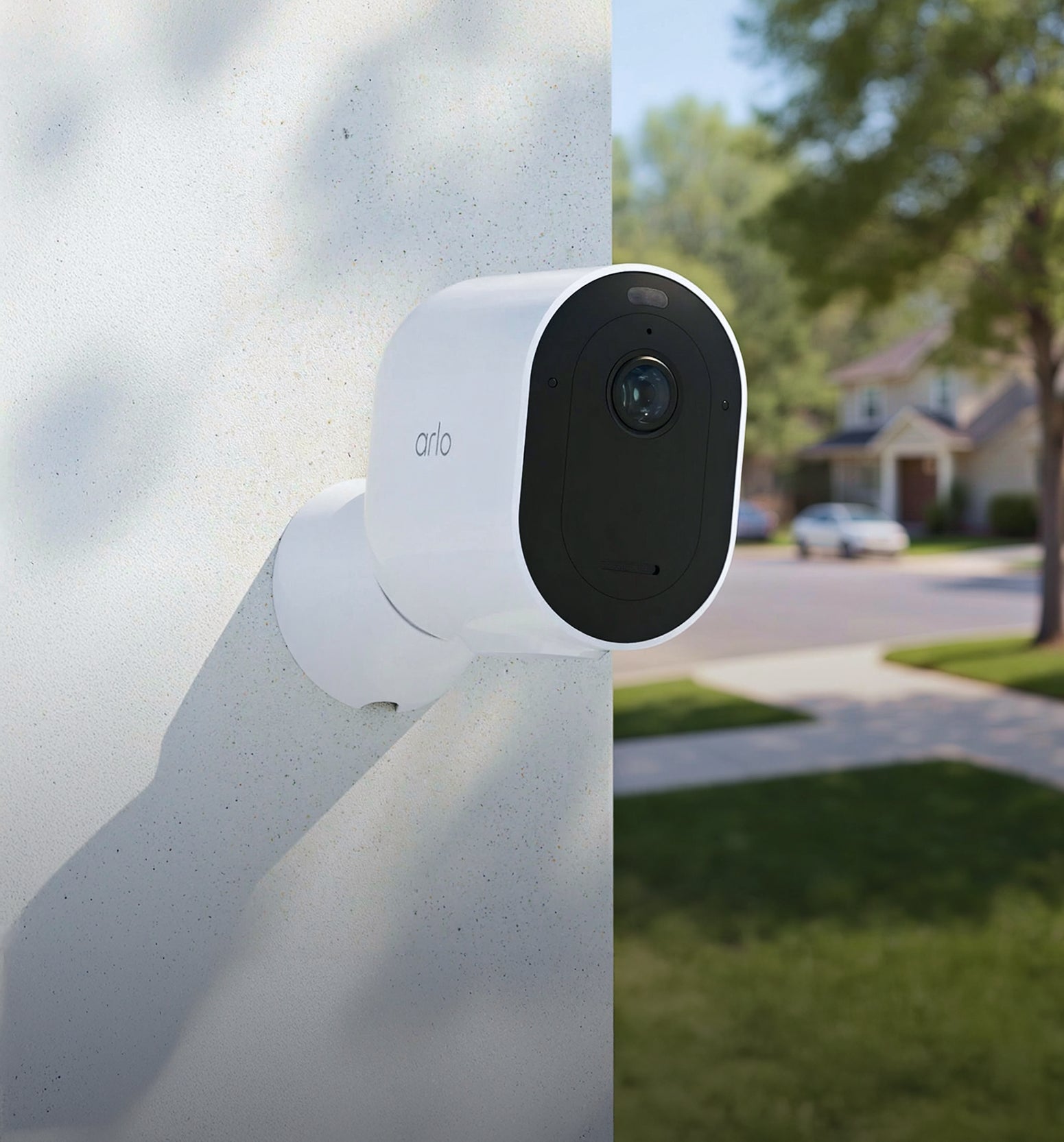Arlo Pro Security Camera (6th Gen) on a wall with a blurred residential street in the background