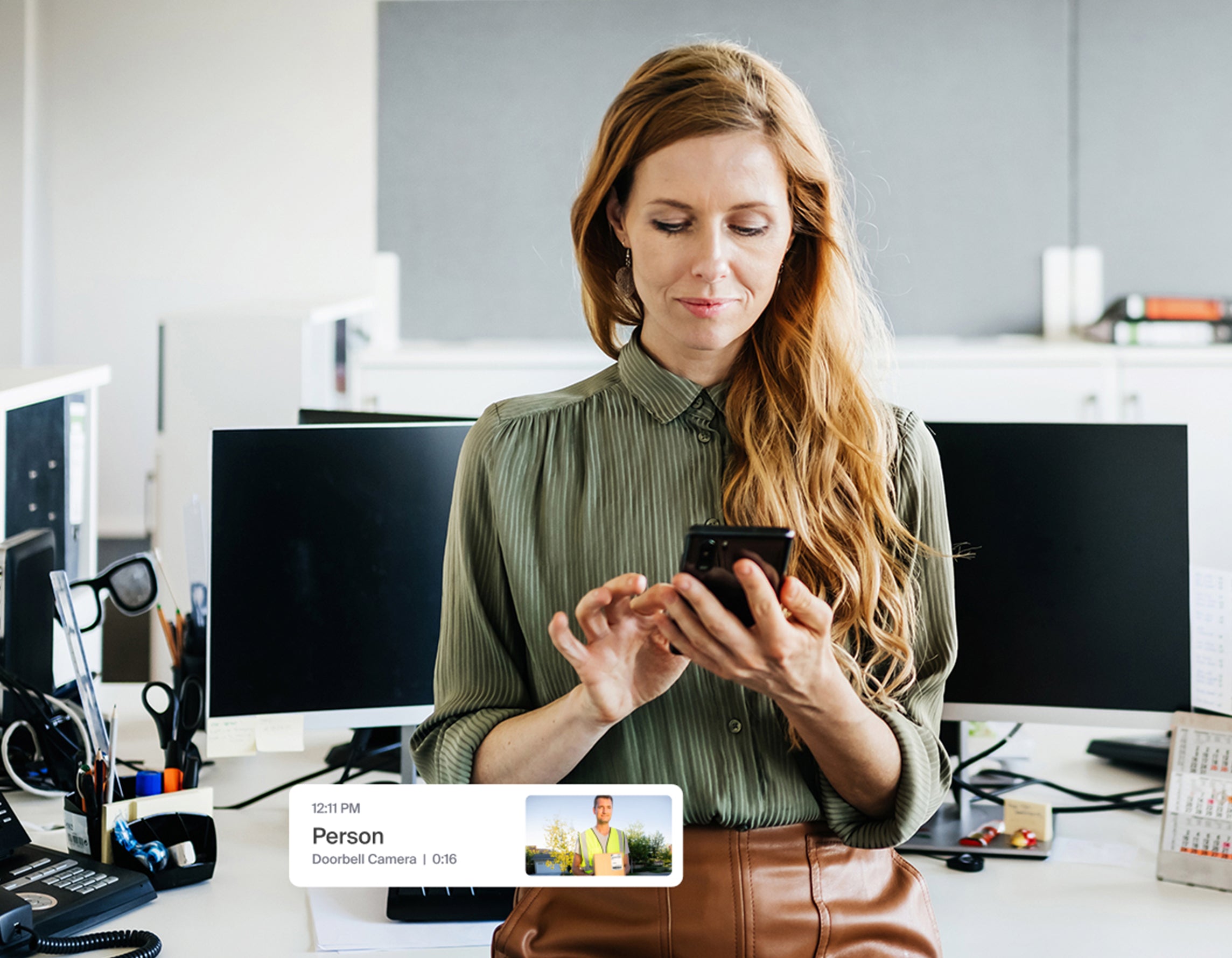 A woman looking at her phone with an Arlo Secure app notification popping up