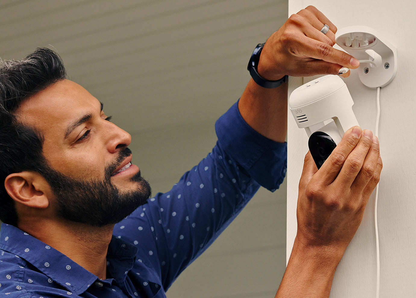 A man plugging in the Arlo Essential Pan Tilt camera outside