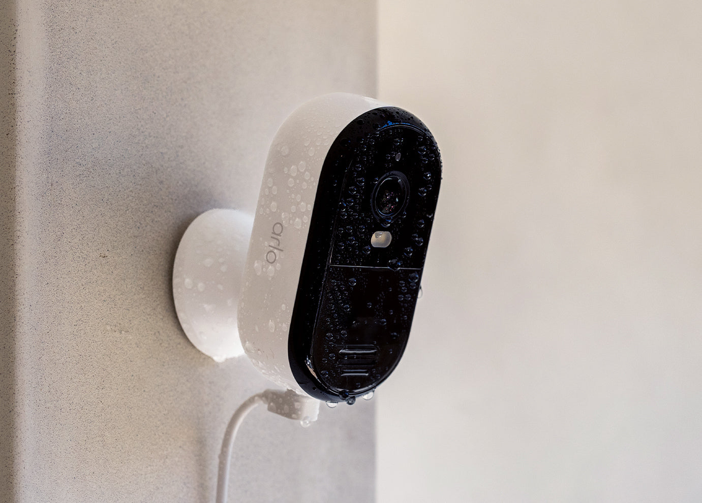 Arlo Essential Plug-in camera mounted on the side of a house in the rain