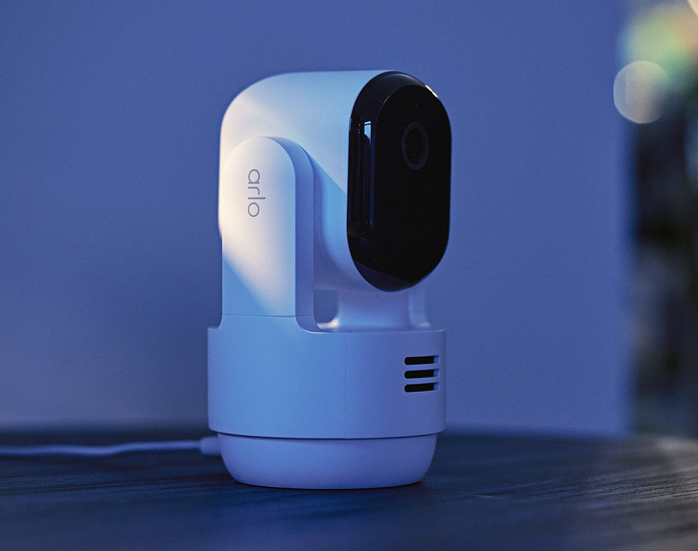 Arlo Essential 3rd Gen Pan Tilt Indoor camera sitting on top of a tablet at night