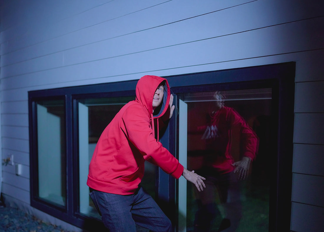 A man trying to break into a window of a house and an Arlo Secure app notification pops up animation