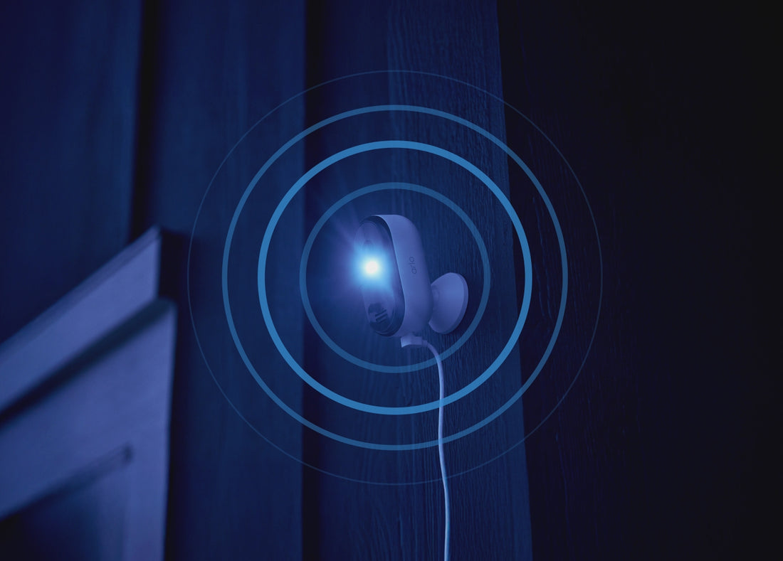 Arlo Essential Plug-in camera mounted on the side of a house with pulsating rings at night animation
