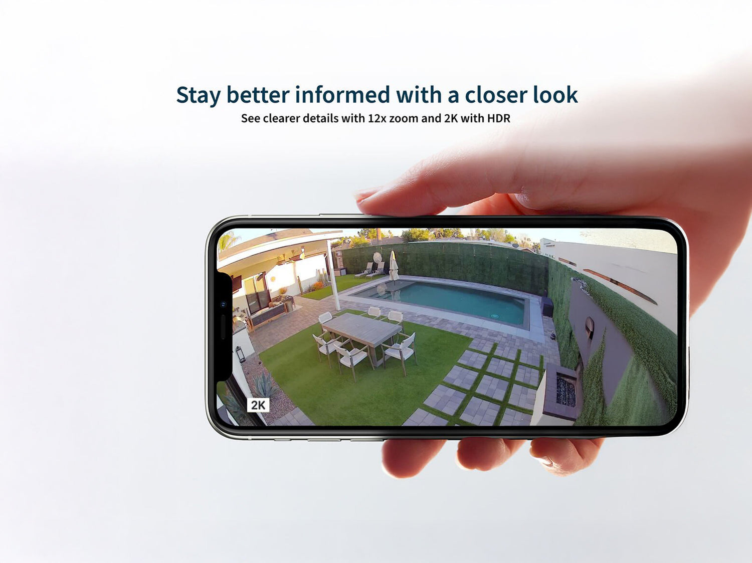 A hand holding a phone with the a backyard with a pool displaying in 2K