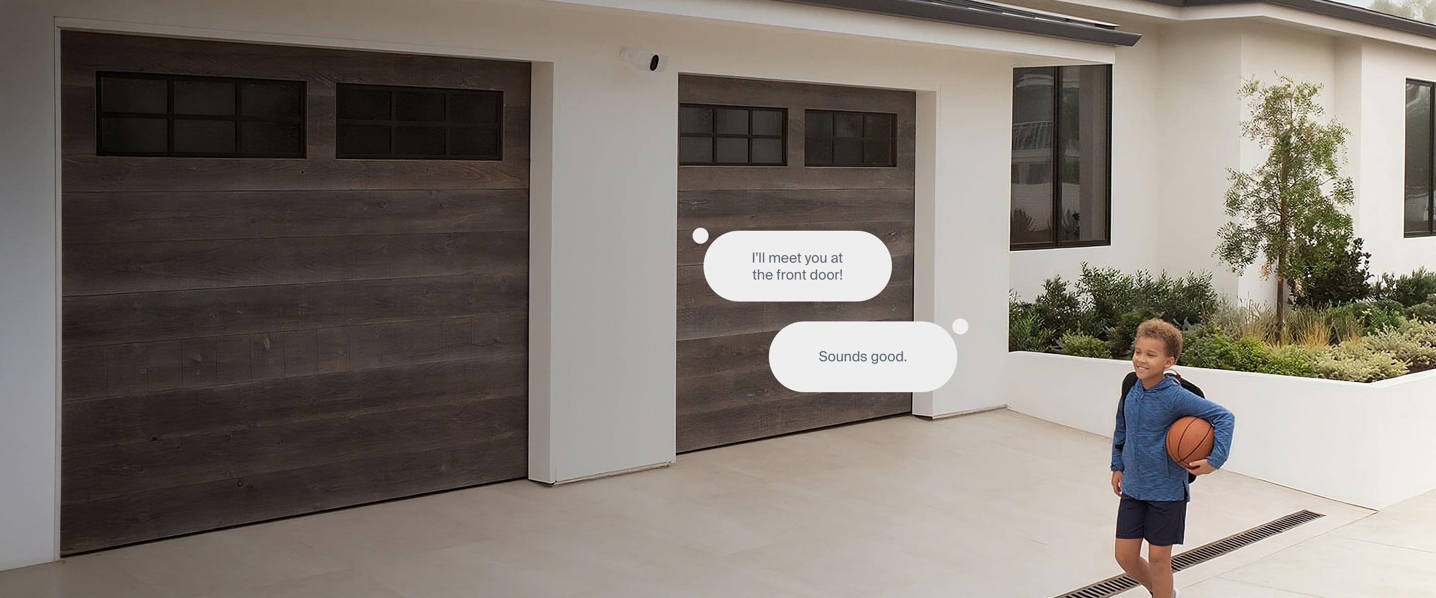 Child walking with basketball in front of garage with Arlo Wireless Floodlight above garage