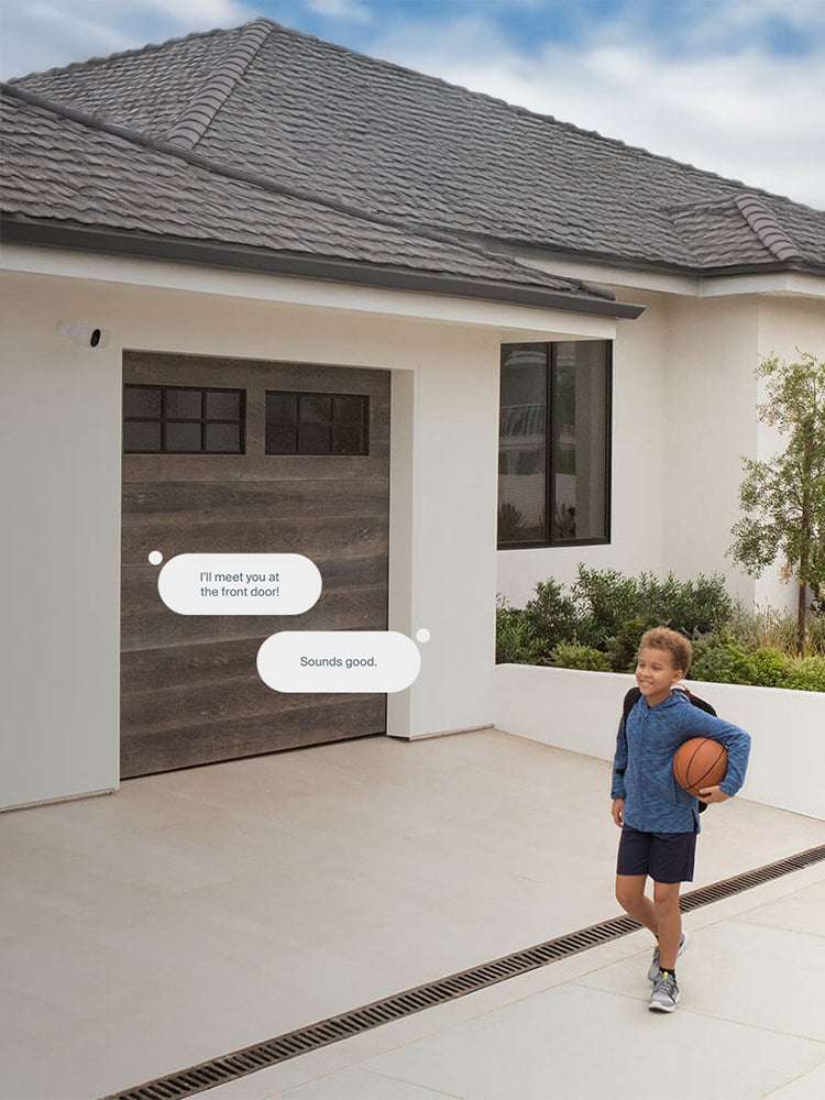 Child walking with basketball in front of garage with Arlo Wireless Floodlight above garage